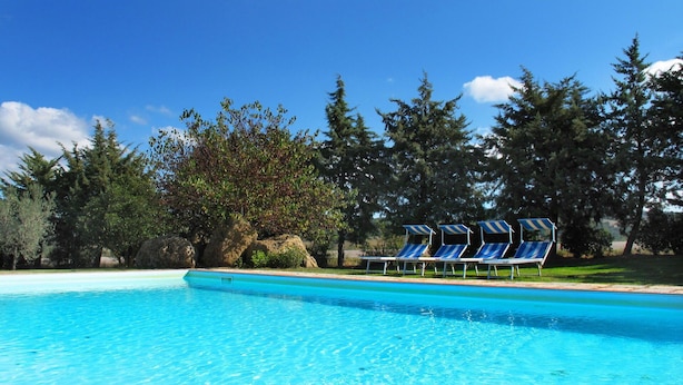 A clear blue swimming pool with lounge chairs and a rocky landscape in the background. - Beautiful apartment in villa for 5 people with WIFI, pool, TV and veranda (Pomarance)