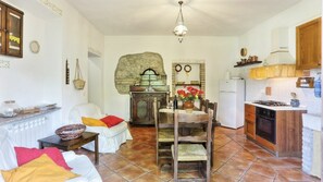 A cozy living room with a fireplace, a dining area with a table and chairs, and a kitchen with a stove and cabinets.