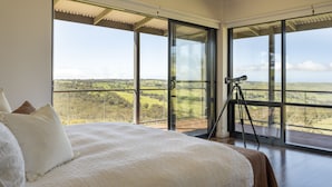 A bedroom with a large bed, a telescope, and a balcony with a scenic view. - Old Coach Road Estate (Hindmarsh Valley)