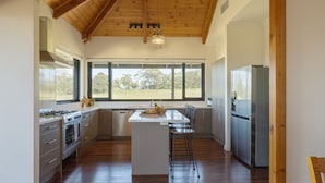 A modern kitchen with a large island, stainless steel appliances, and a view of the outdoors. - Old Coach Road Estate (Hindmarsh Valley)