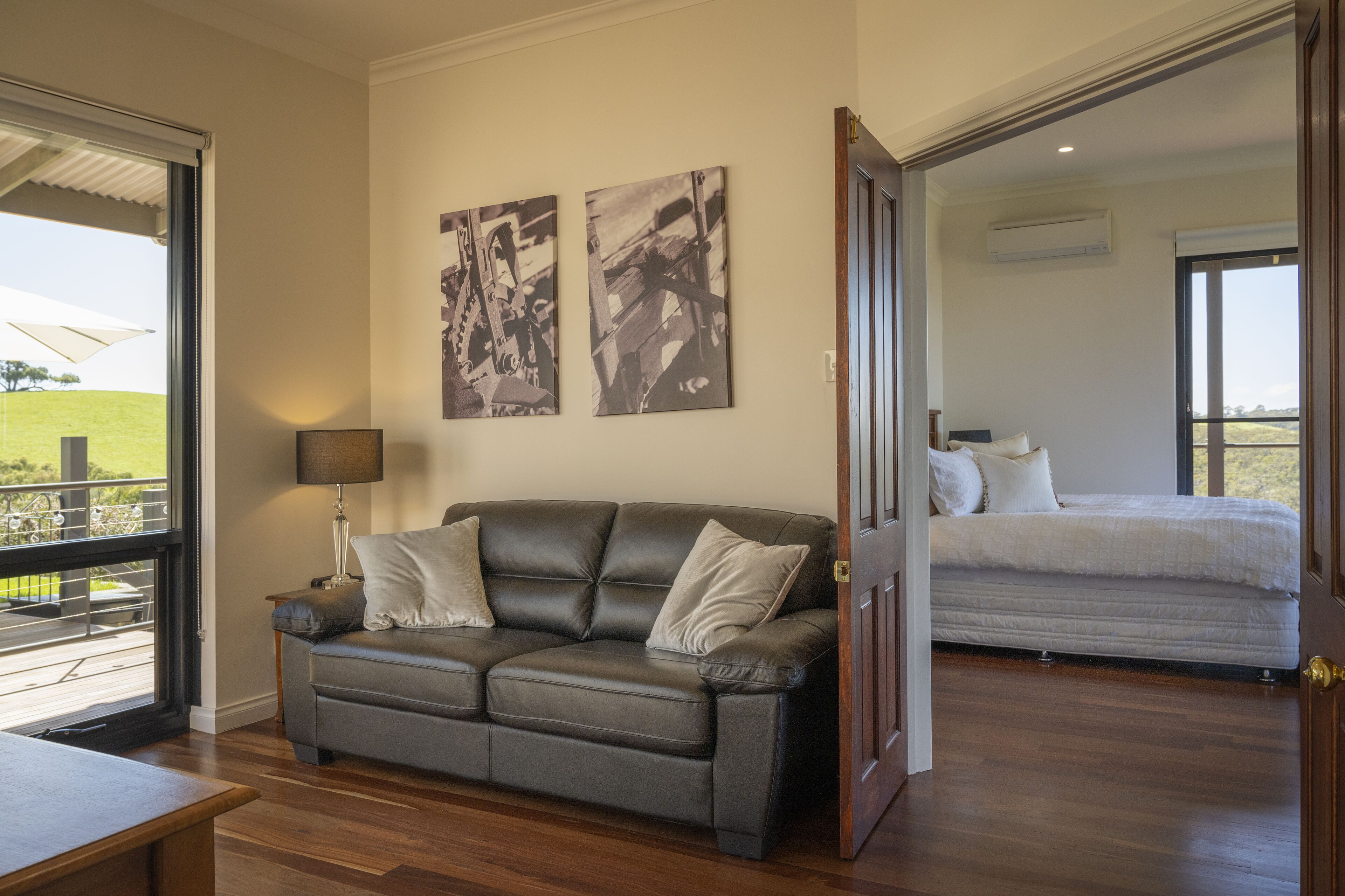 Una sala de estar moderna con un sofá de cuero, una mesa de comedor y un amplio ventanal con vistas a un paisaje verde.