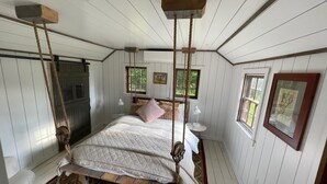 Ein rustikales Schlafzimmer mit einem hölzernen Bett, einem Hängesessel und einem kleinen Nachttisch mit Lampe.