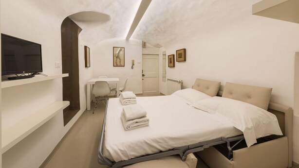 Une chambre d’hôtel moderne équipée d’un lit, d’un bureau, d’une chaise, d’une télévision et d’une salle de bain.