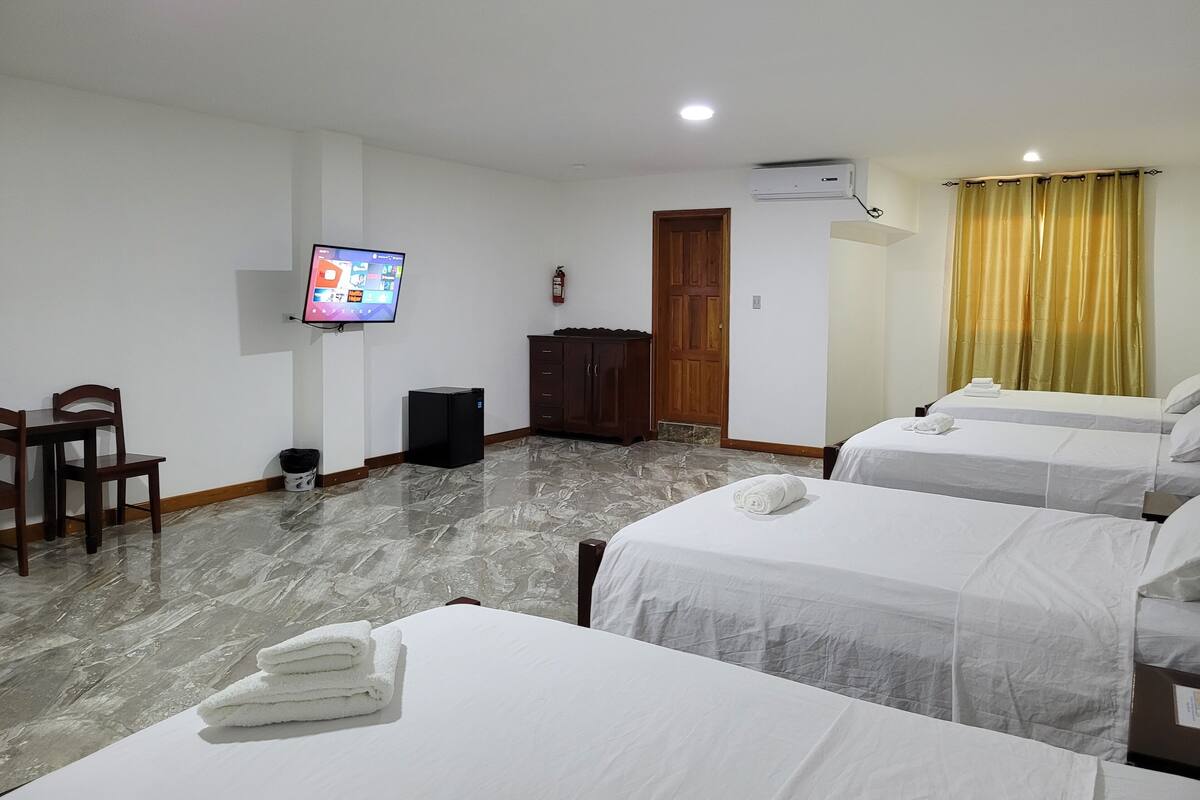A hotel room with two beds, a TV, a wardrobe, and a marble floor.