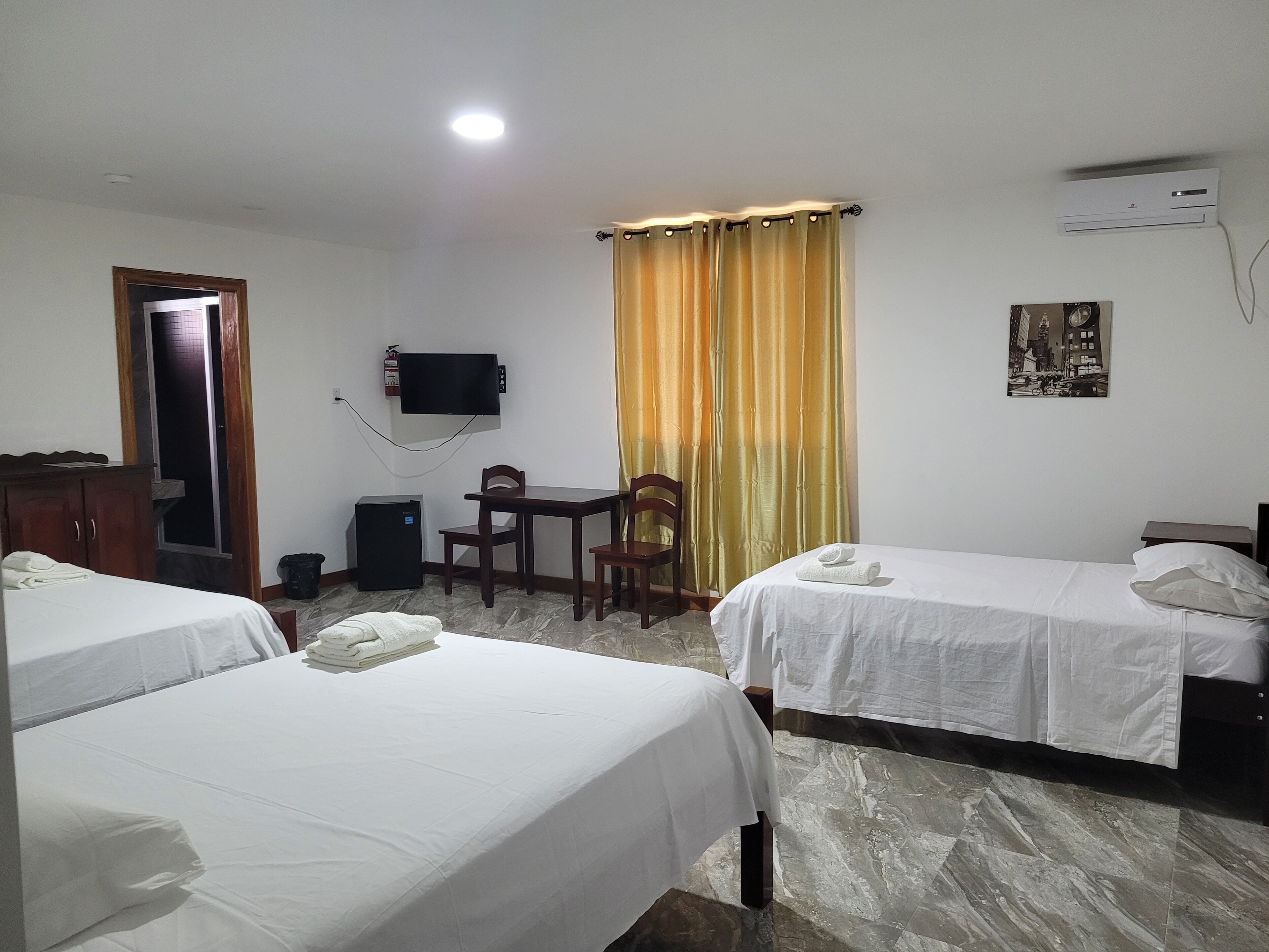 A hotel room with two beds, a desk, a chair, a television, and a picture on the wall.