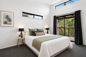 A bedroom with a bed, two bedside tables, a nightstand, a window with curtains, a framed picture on the wall, and a view of trees outside. - Top of the Bay by Ready Set Stay (Arthurs Seat)