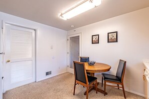 A dining area with a round table, two chairs, and framed artwork on the wall. - Sunny Home in Private Setting (Rochester)