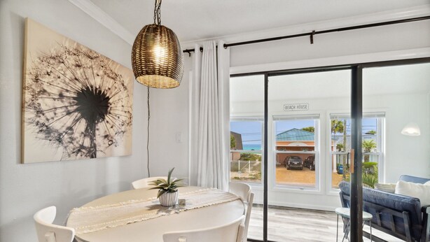 A dining area with a round table, white chairs, a woven pendant light, and a large abstract painting on the wall.