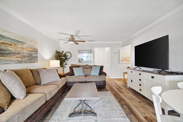 A living room with a sofa, coffee table, TV, and a ceiling fan.