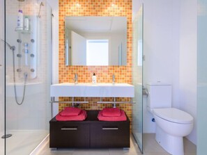 A modern bathroom with a glass shower enclosure, a white sink with a mirror above, and a toilet. - Porte Venere by Interhome (Moncofar)