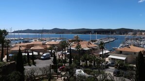 Marina con barcos, zona de estacionamiento y edificios con techos de tejas rojas.
