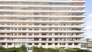 Un hotel de varios pisos con balcones en cada planta, una entrada central y un jardín ajardinado al frente.