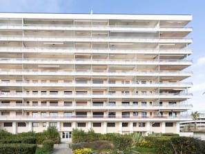 A multi-story hotel with balconies on each floor, a central entrance, and a landscaped garden area in front. - Le Grand Large by Interhome (Le Lavandou)