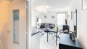 Une pièce moderne et bien éclairée, comprenant un coin repas, un canapé et une petite cuisine.