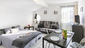 Une chambre d’hôtel moderne dotée d’un grand lit, d’un bureau avec une chaise, d’une télévision et d’une fenêtre avec des rideaux.