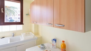 A kitchen with a sink, a window, and a breakfast table with croissants, a carton of milk, and a bottle of orange juice. - Le Grand Large by Interhome (Le Lavandou)