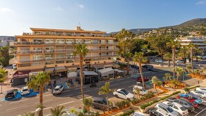 A multi-story hotel with balconies, a parking lot, and palm trees. - Le Grand Large by Interhome (Le Lavandou)