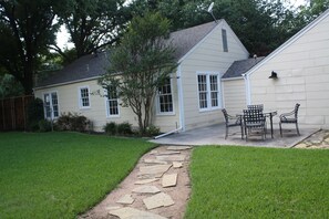 A house with a stone pathway leading to a patio with outdoor furniture.