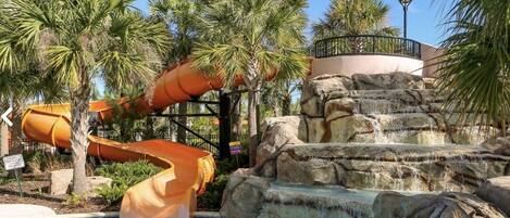 A water slide, a pool, and a rock formation.