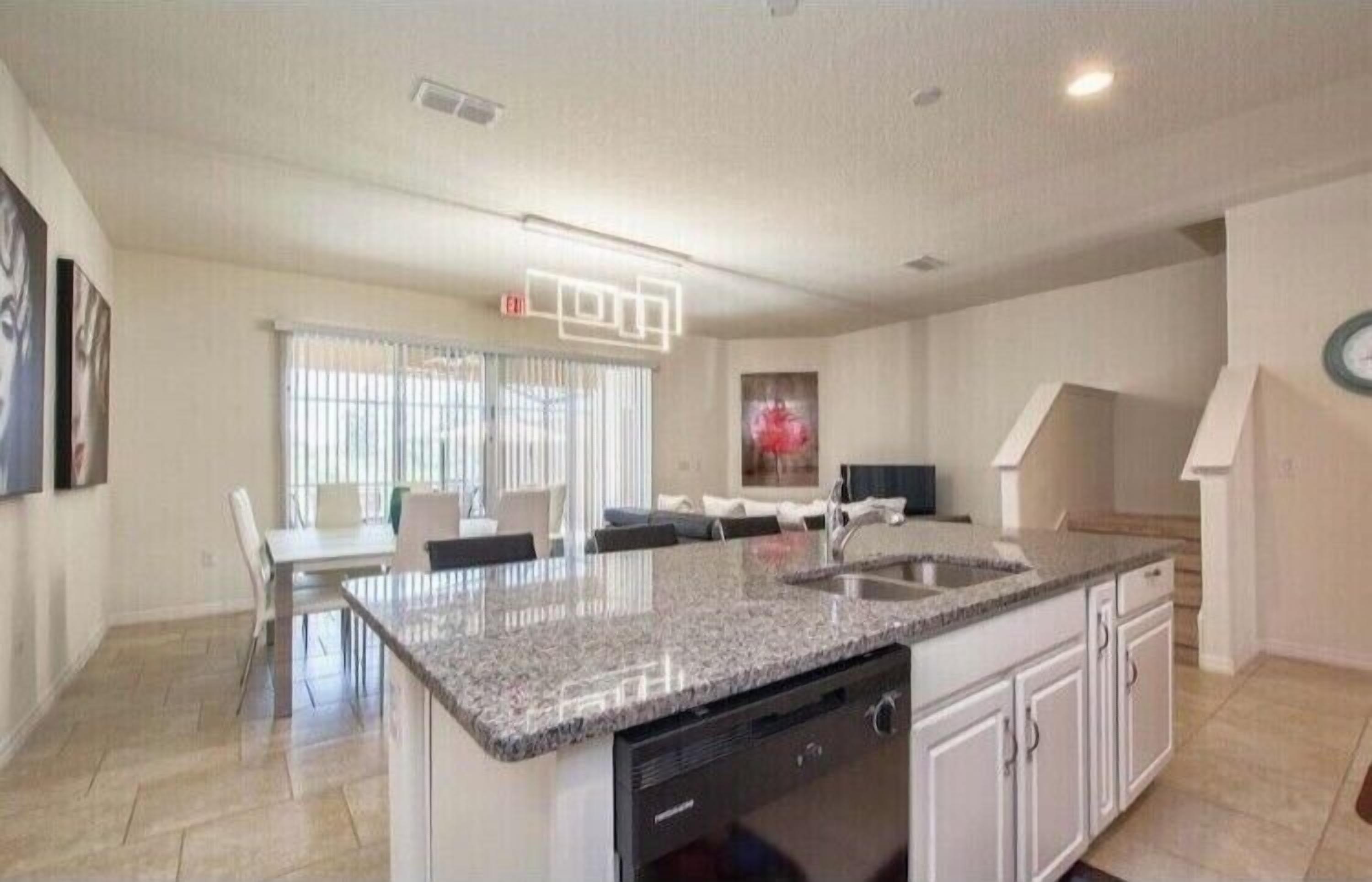 A modern kitchen with granite countertops, white cabinetry, and a built-in dishwasher.