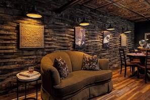 Um quarto acolhedor com parede de madeira, um sofá confortável e uma pequena mesa com um livro e um copo.