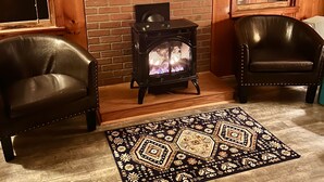Una habitación acogedora con chimenea, dos sillones de cuero, un tapiz estampado y paredes de madera.