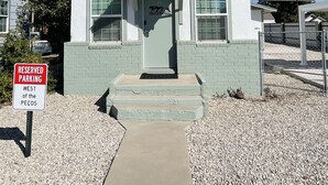 Een laag gebouw met een witte gevel en groene accenten, met een deur waarop staat 