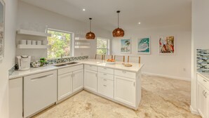 A modern kitchen with white cabinetry, a large island, and pendant lighting. - Newly Renovated Beach House w Heated Pool, 4 BR, 3 BA (Fort Lauderdale)