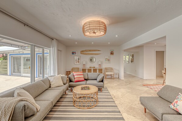 A spacious living room with a large sofa, a round coffee table, and a modern ceiling light.
