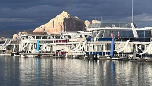 Ein Yachthafen mit vor Anker liegenden Booten, ein Felsen im Hintergrund und ein bewölkter Himmel.