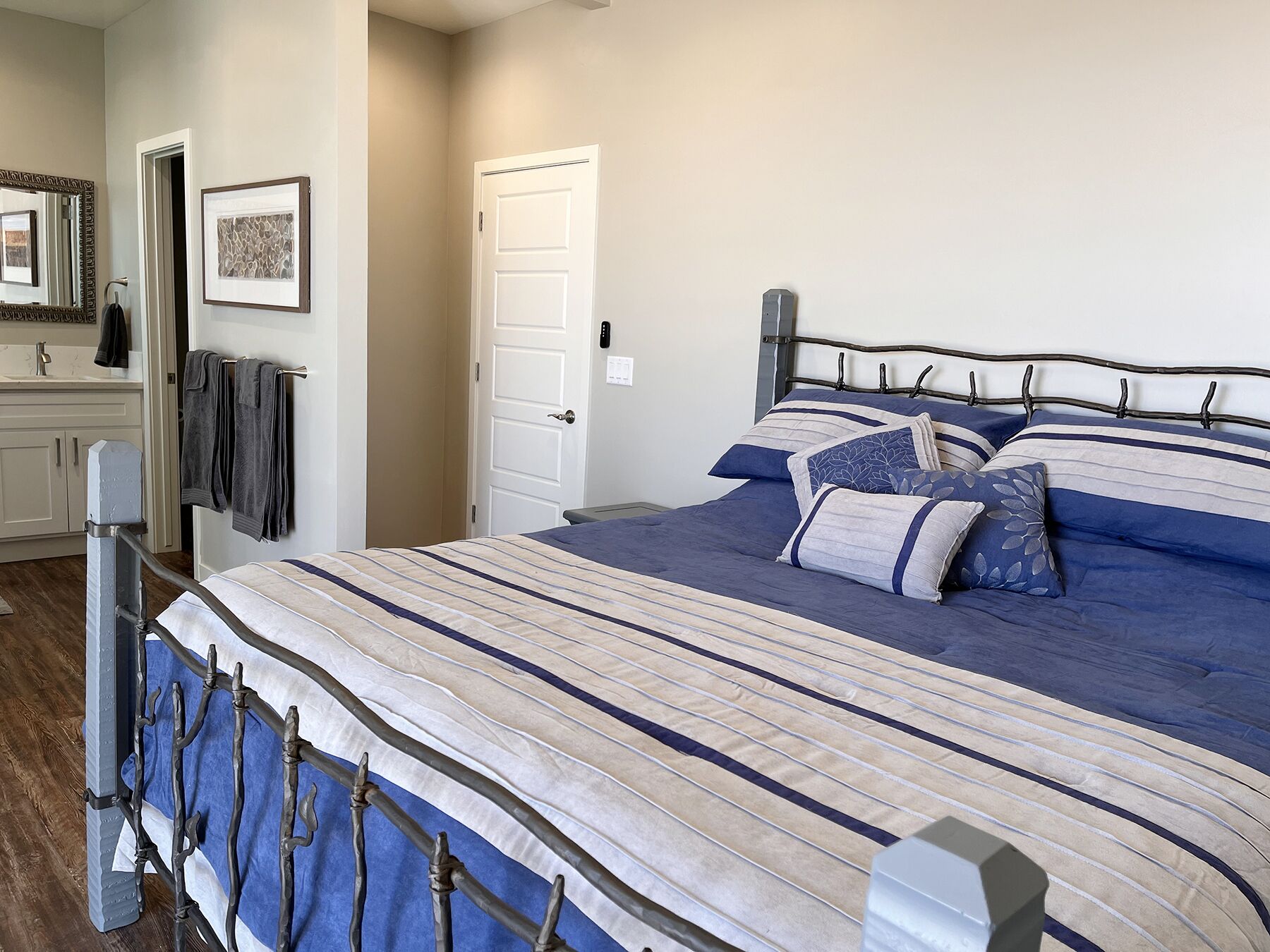 A bedroom with a bed, a nightstand, a dresser, a mirror, and a door.
