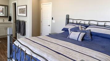 A bedroom with a bed, a nightstand, a dresser, a mirror, and a door.