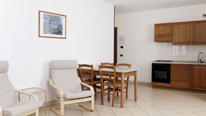 A modern kitchen with wooden cabinets and a dining area with two chairs and a table.