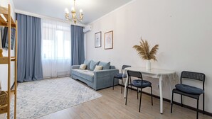 Uma sala de estar moderna com um sofá, cadeiras, uma mesa de jantar e um lustre.