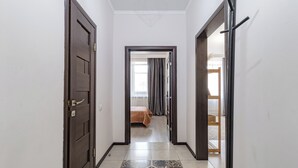 Um corredor com piso estampado que leva a um quarto com cama e cortinas.