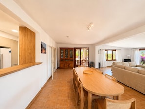 A spacious living area with a wooden dining table, a sofa, and a view of the outdoors.