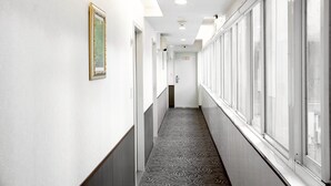 A hallway with patterned flooring, a framed picture on the wall, and large windows on one side. - Star Ximen (Taipei)