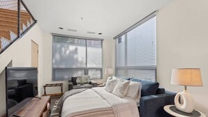 Une chambre à coucher moderne avec un lit, un canapé, une télévision et une lampe.