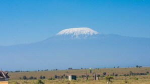 A mountain with a snow-capped peak, a small building, and a clear sky.
