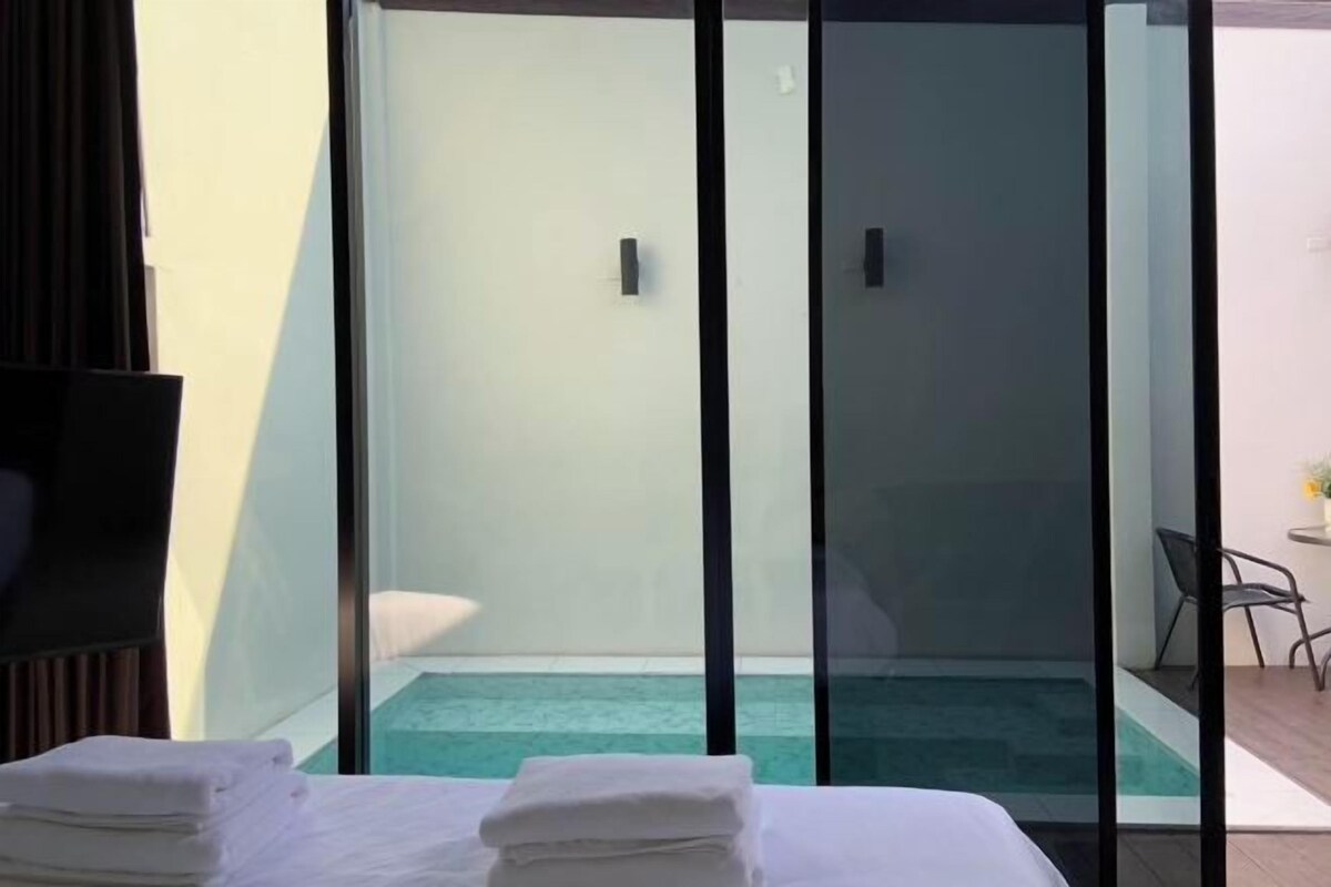 A hotel room with a bed, a small pool, and a sliding glass door leading to a balcony.