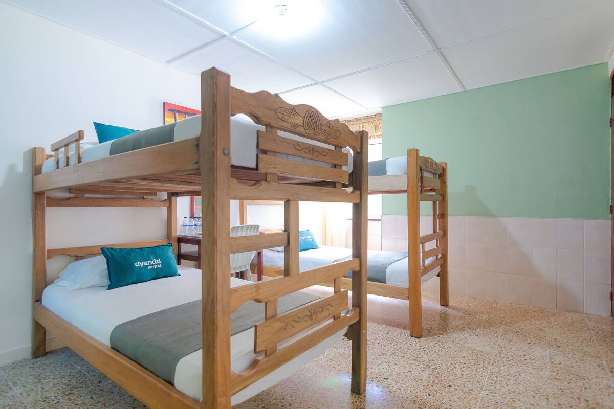 A bunk bed room with a wooden headboard, a blue pillow, and a green blanket.