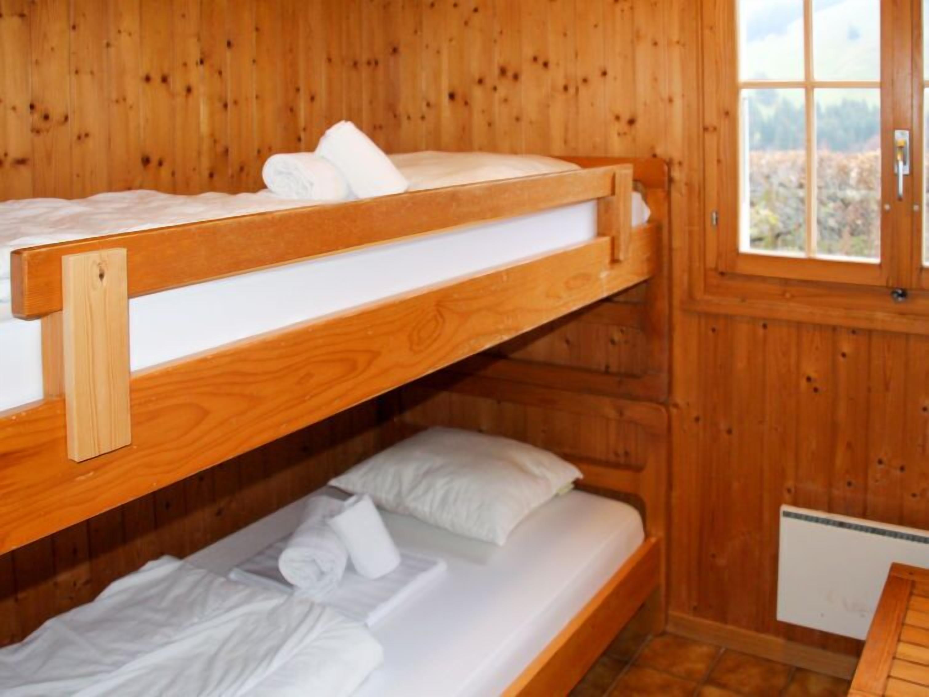 Habitación con literas, paredes de madera y ventana.