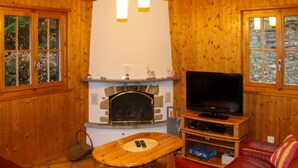 Een gezellige woonkamer met een open haard, een televisie en een rode leren bank.