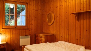 Een kamer met houten lambrisering, een bed, een kast, een spiegel en een raam.