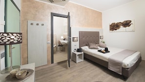 A modern hotel room with a bed, bedside table, and a bathroom visible through an open door. - Hotel Doge (Rimini)