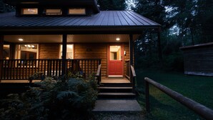 Een houten vakantiehuis met een veranda, trappen naar de ingang en een rode deur.