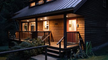 Guests can enjoy the cabin's porch with two windows and doors, surrounded by lush greenery.