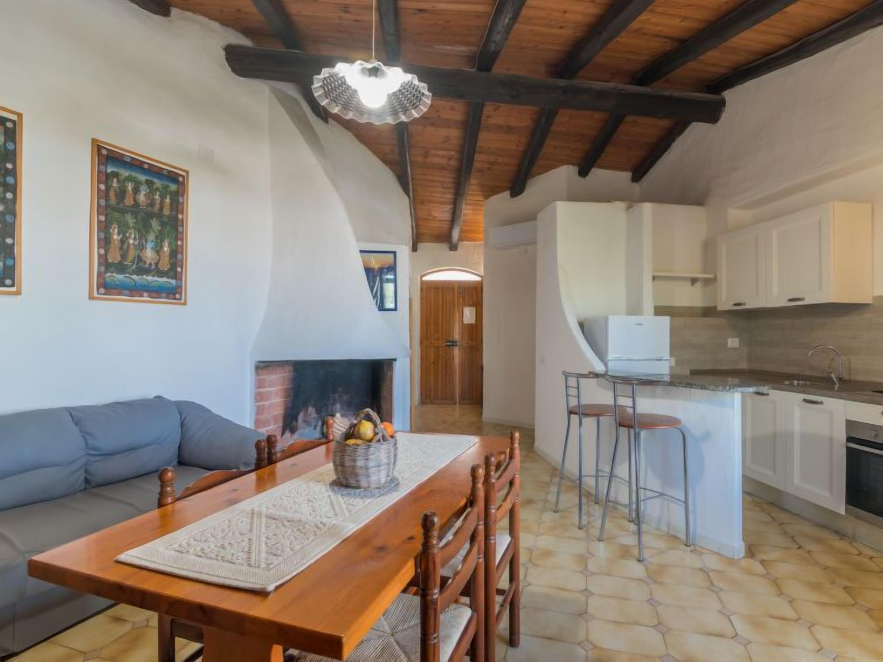 Un accogliente soggiorno con camino, un tavolo da pranzo e una zona cucina con pensili bianchi e uno sgabello da bar.