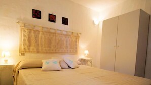 Ein Schlafzimmer mit einem Bett, zwei Nachttische mit Lampen, einem Kleiderschrank und drei an der Wand hängenden Bildern.