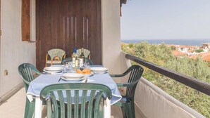 Ein Balkon mit Tisch für zwei Personen, mit Blick auf eine Küstenlandschaft.